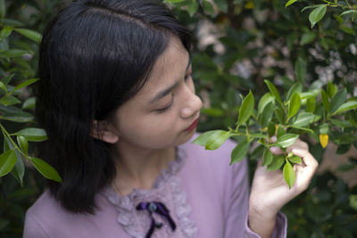 Close-up of girl holding plant standing outdoors