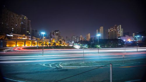 Light trails on city street by buildings at night