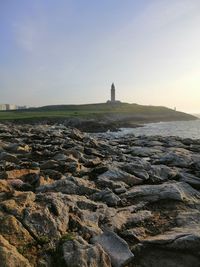 Scenic view of sea and rocks against sky during sunset