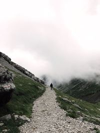 Rear view of man walking on mountain against sky