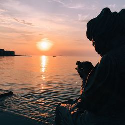 Sculpture by sea against sky during sunset
