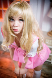 Close-up portrait of beautiful young woman standing against pink background