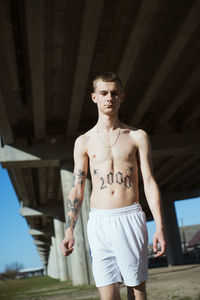 Low angle view of shirtless young man standing outdoors