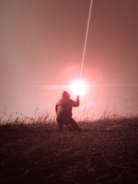 Man standing on field against sky during sunset
