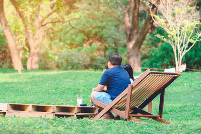 Rear view of couple sitting on deck chair at park