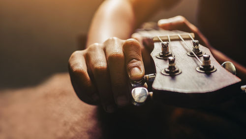 Cropped hands of man adjusting guitar