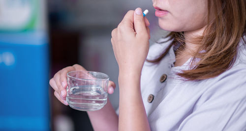 Midsection of woman drinking glass with water