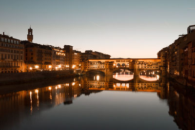 Reflection of illuminated buildings and ponte vecchio bridge in florence, italy