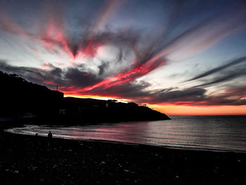Scenic view of sea against dramatic sky during sunset