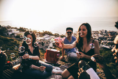 Group of people sitting at park against city