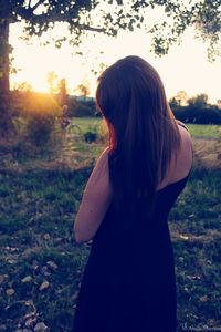 Rear view of woman standing on field against sky