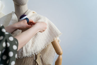 Cropped image of woman adjusting fabric on mannequin