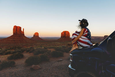 Usa, utah, woman with united states of america flag enjoying the sunset in monument valley