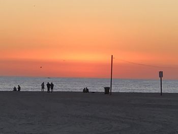 Silhouette people on beach against sky during sunset