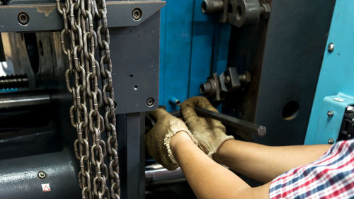 Cropped hands of woman repairing machine in workshop