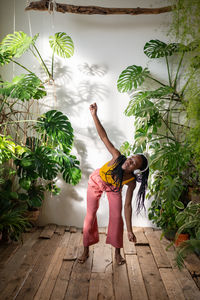 Positive black girl dancing barefoot on wooden floor in headphones listening to music enjoy moment.