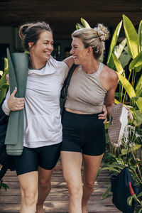 Happy female friends walking with arms around at wellness resort