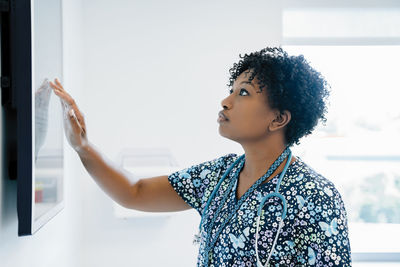 Female doctor touching flat screen while working in hospital