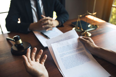 Midsection of people reading book on table