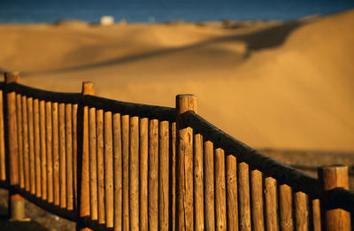 Fence by railing against sky during sunset