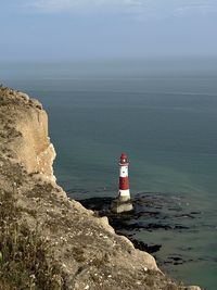 Lighthouse by sea against sky