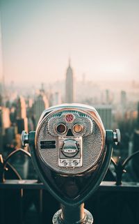 Close-up of coin-operated binoculars against cityscape