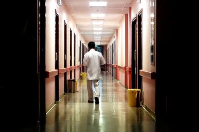 Rear view of man walking in corridor of building