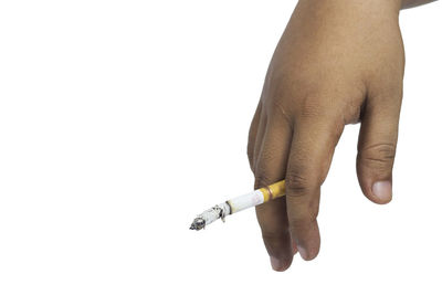 Close-up of hand holding cigarette against white background