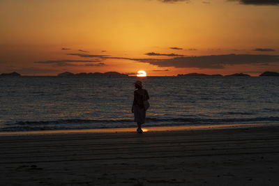 Full length of woman standing on beach during sunset