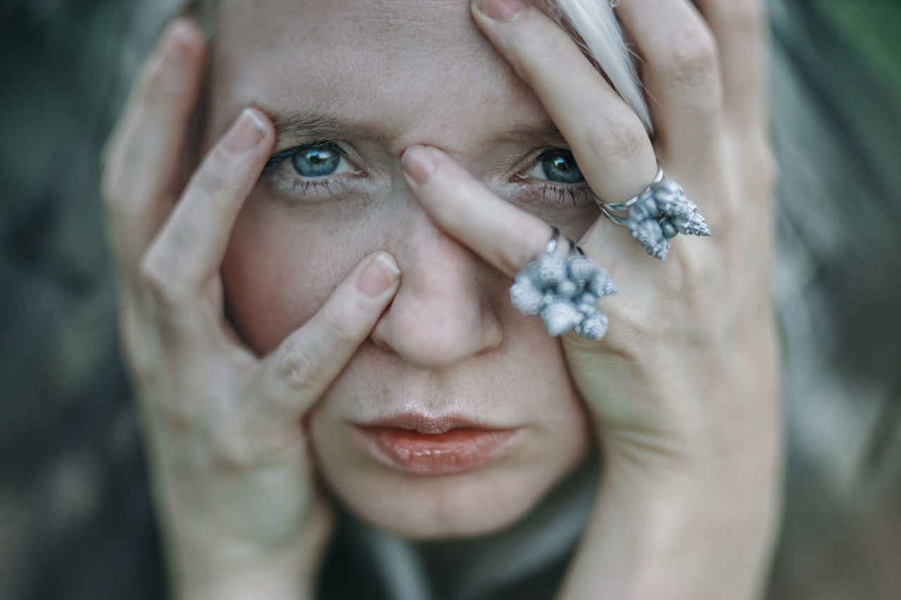 CLOSE-UP PORTRAIT OF WOMAN WITH HAND ON HAIR