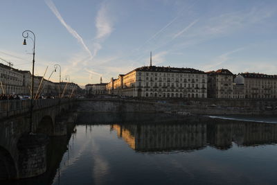 Bridge over river in city against sky