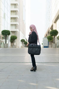 Full length of businesswoman wearing hijab and suit standing in city