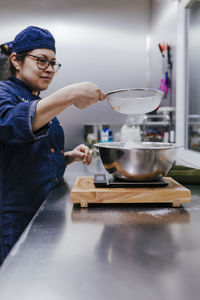 Side view of woman preparing food in kitchen