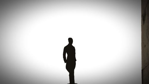 Rear view of silhouette man standing against sky