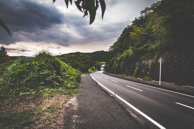 Empty road against cloudy sky