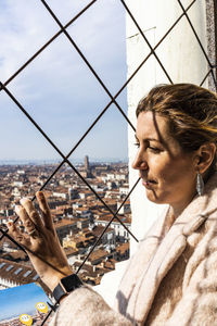 Woman looking through window in city