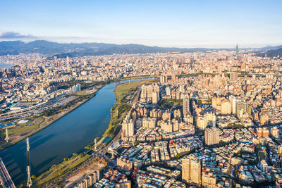 High angle view of city by river against sky