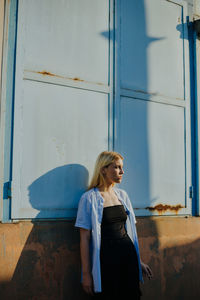 Woman looking away while standing against building