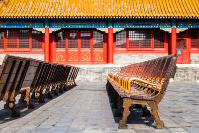 Empty bench on sidewalk by building in city forbidden city