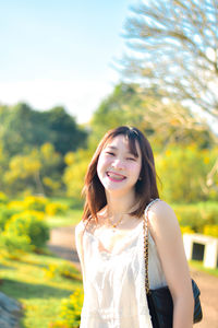 Portrait of young woman standing against trees