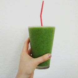 Close-up of cropped hand holding paper over white background
