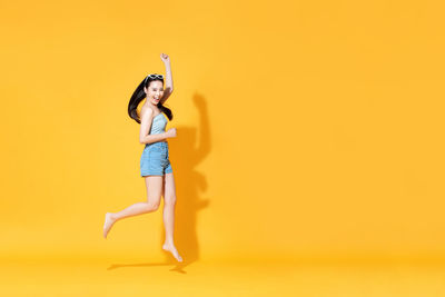Full length of woman standing against yellow background