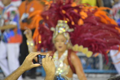 Cropped image of man photographing dancer at carnival