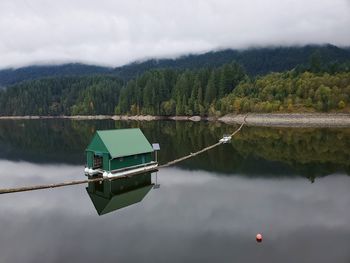 Scenic view of lake against sky with reflections of a service house