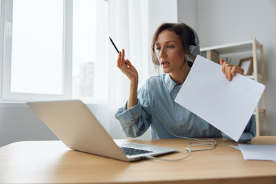 Portrait of businesswoman using laptop while sitting on table