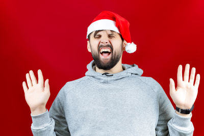 Portrait of young man wearing hat against red background