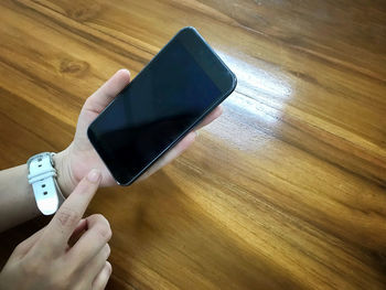 Midsection of person using mobile phone on hardwood floor