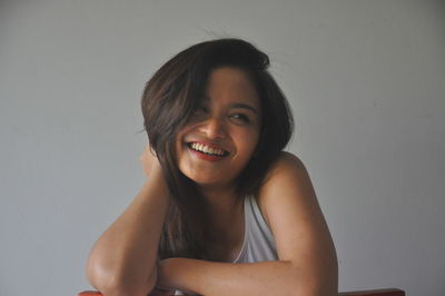 Portrait of smiling young woman against white background