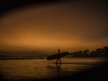 Sunset on the beach - surfer at barra da tijuca beach, rio de janeiro