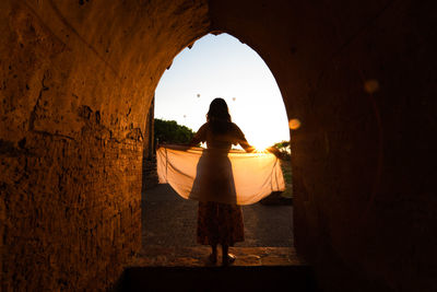 Rear view of woman standing at archway